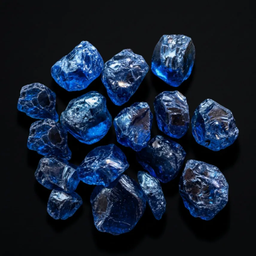 A parcel of rough blue sapphire crystals on a black background, showing natural crystal faces and colour zoning